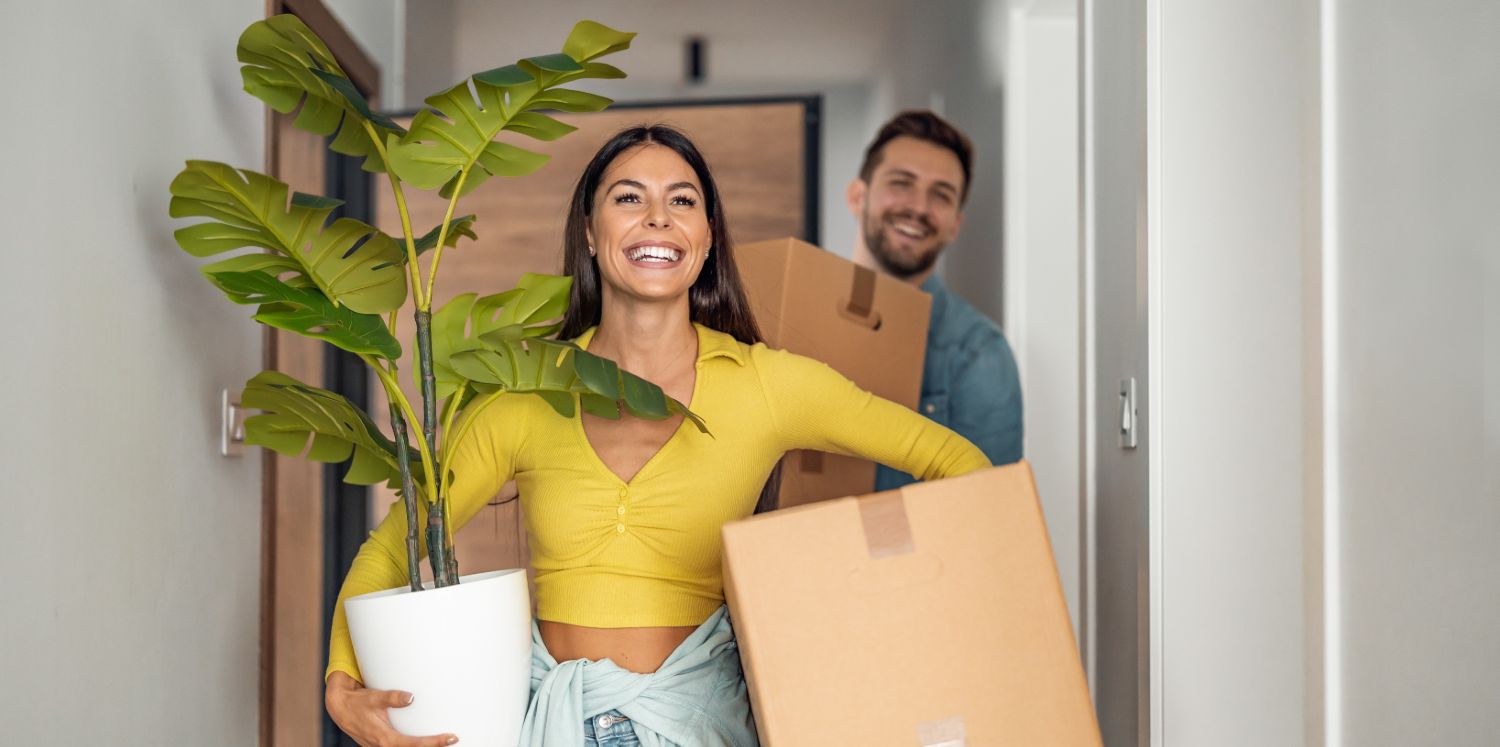 new_home A young couple smiling carrying boxes into their new home